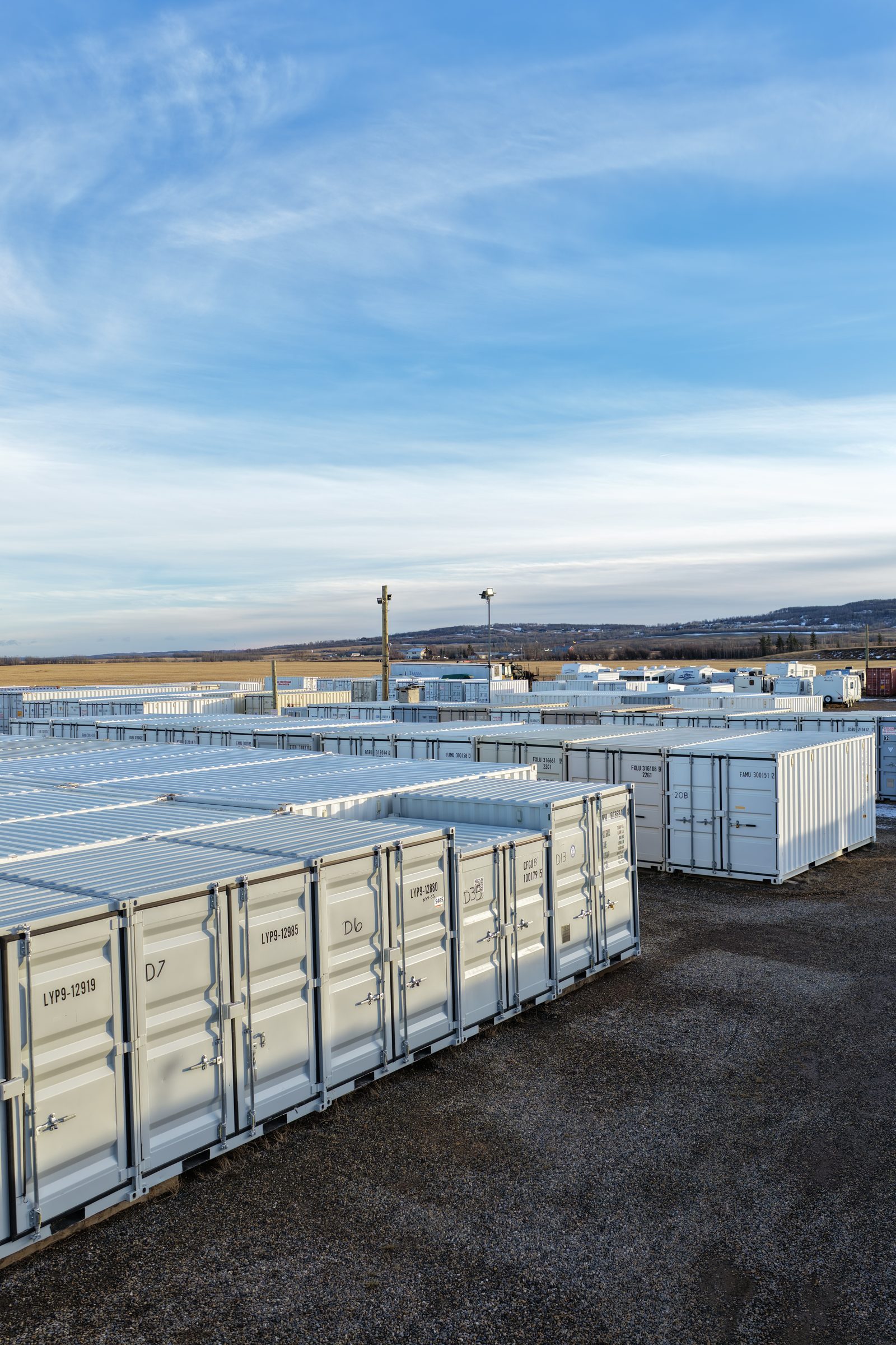 Looking down a row of 40 ft containers at Ace High Storage under a blue sky